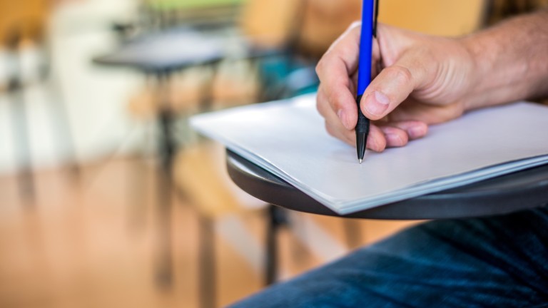 A man is writing/signing on a paper. Focused on a hand with pen